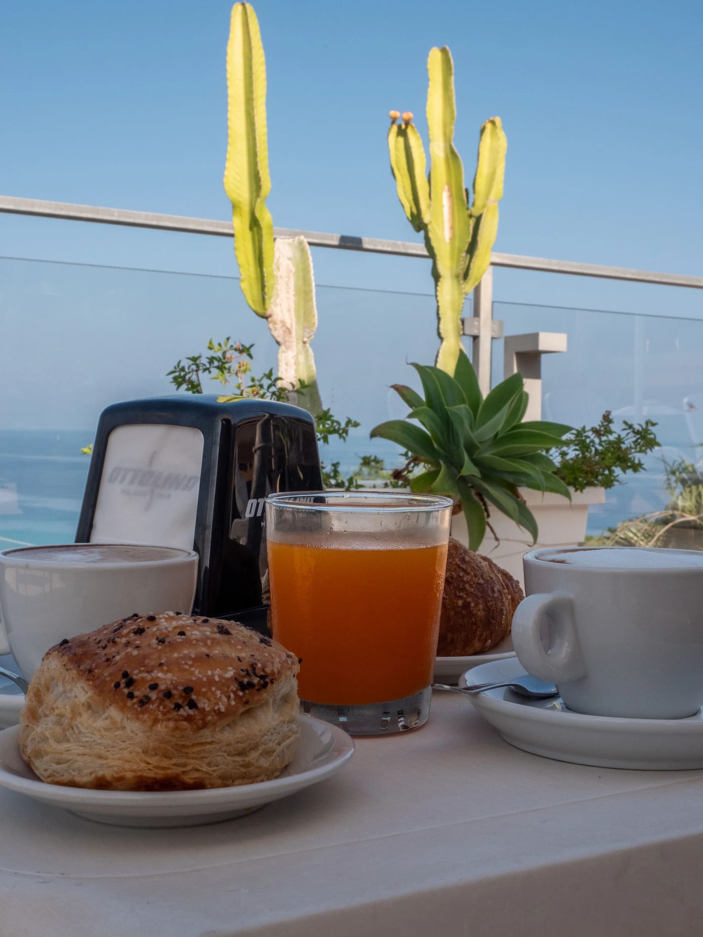 Colazione all'aperto vista mare con tazze di cappuccino, succo d'arancia e cornetto sulla terrazza dell'Airone Residence Zambrone.