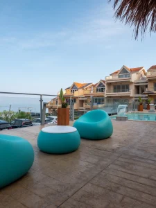 Terrazza solarium dell'Airone Residence Zambrone con poltrone lounge turchesi, pavimento effetto legno e piscina vista mare in Calabria.