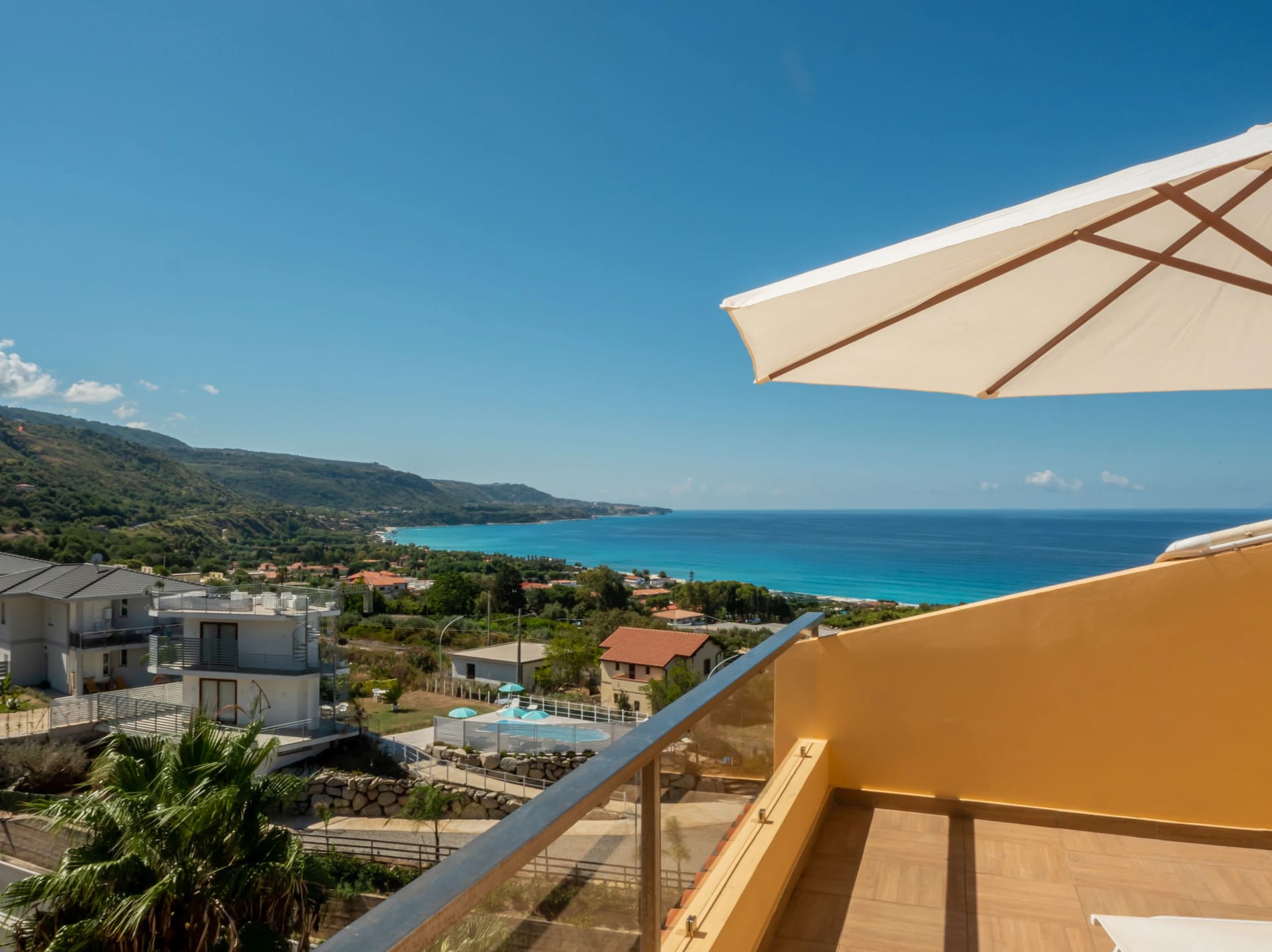 Terrazzo panoramico con ombrellone bianco e vista mozzafiato sul mare turchese e cristallino dall'Airone Residence Zambrone.